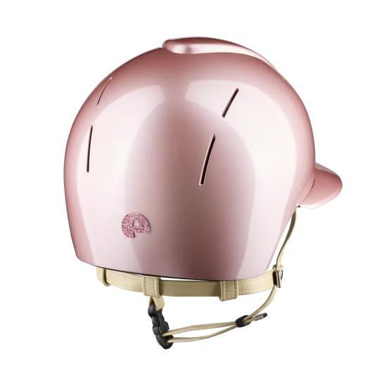 A glossy metallic pink helmet with a matching beige chin strap and a small pink graphic logo on the side, shown against a plain white background.