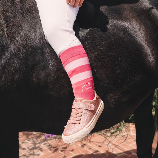 Child's leg on a horse wearing pink socks and pink shoes