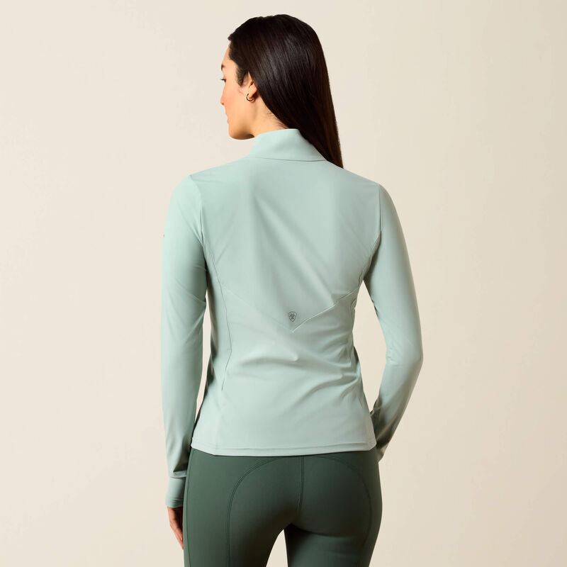 Person wearing a light blue long-sleeve athletic top and green leggings on a beige background