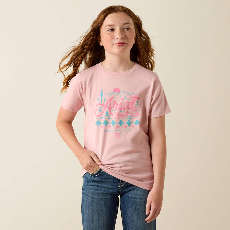 Person wearing a pink t-shirt with text and graphics on a plain background