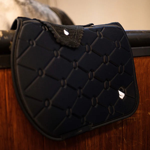 Black Samshield saddle pad and fly veil on a wooden stable door