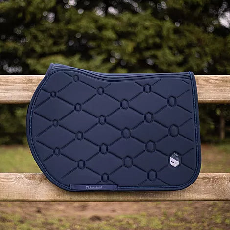 Navy blue quilted saddle pad on a wooden surface with blurred greenery in the background