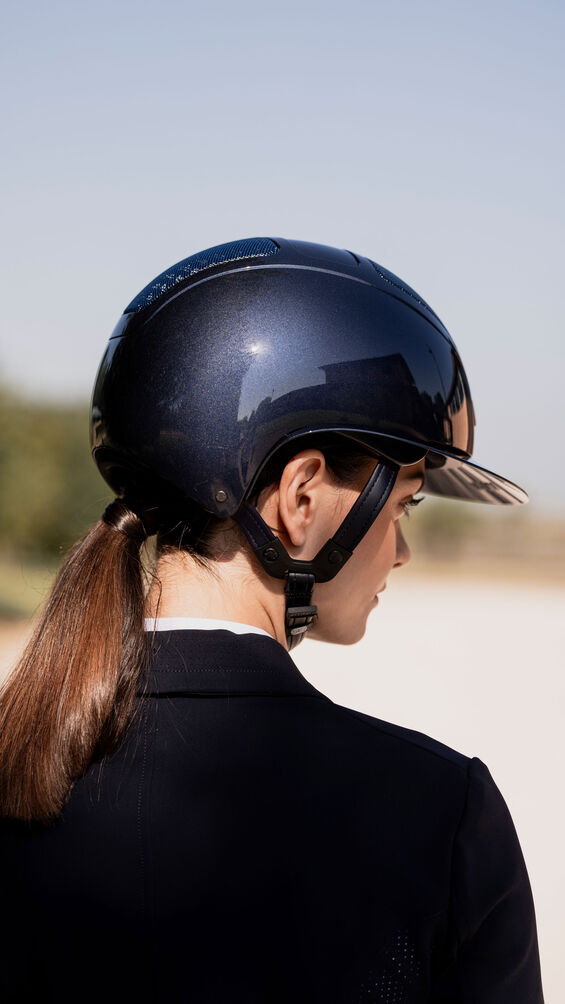 Woman wearing a shiny navy helmet on a blurred background