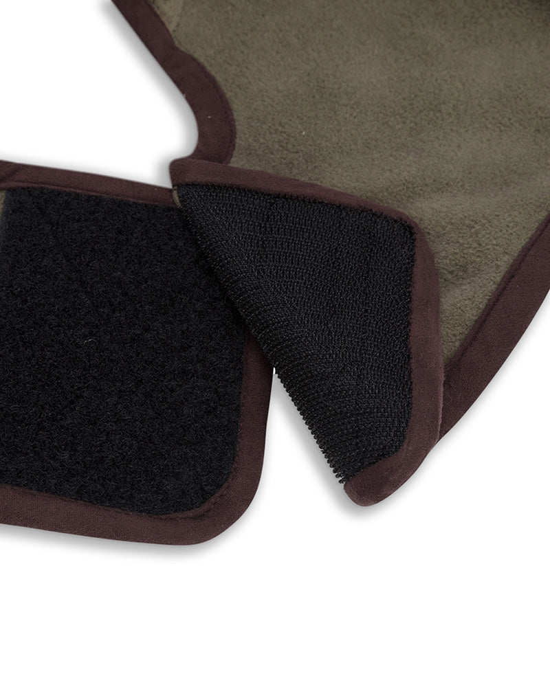 Fastening of a green dog coat with brown trim on a white background