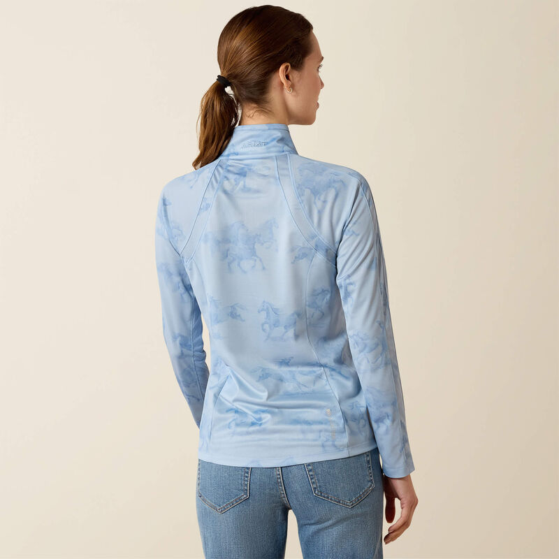 Woman wearing a light blue long-sleeve top with a subtle pattern on a beige background