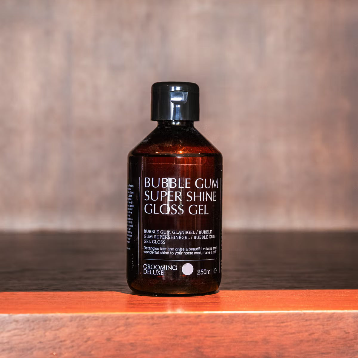 Bottle of Bubble Gum Super Shine Gloss Gel on a wooden surface with a blurred background