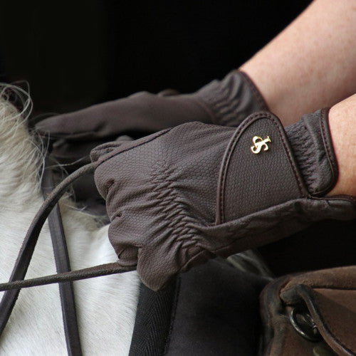 Close-up of a gloved hand holding a horse bridle with a dark background