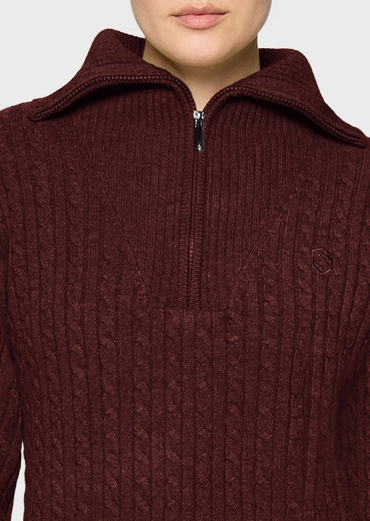 A close-up of a person wearing a ribbed, cable-knit half-zip sweater in a deep burgundy or maroon color, featuring a small embroidered logo on the chest.