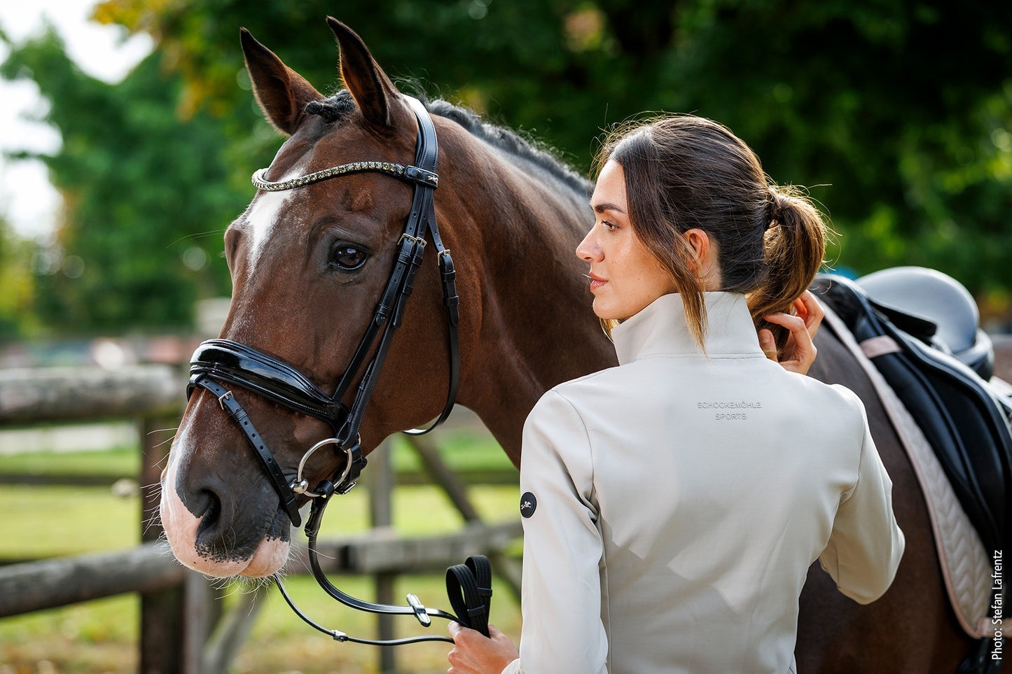 Woman in equestrian attire standing next to a horse outdoors