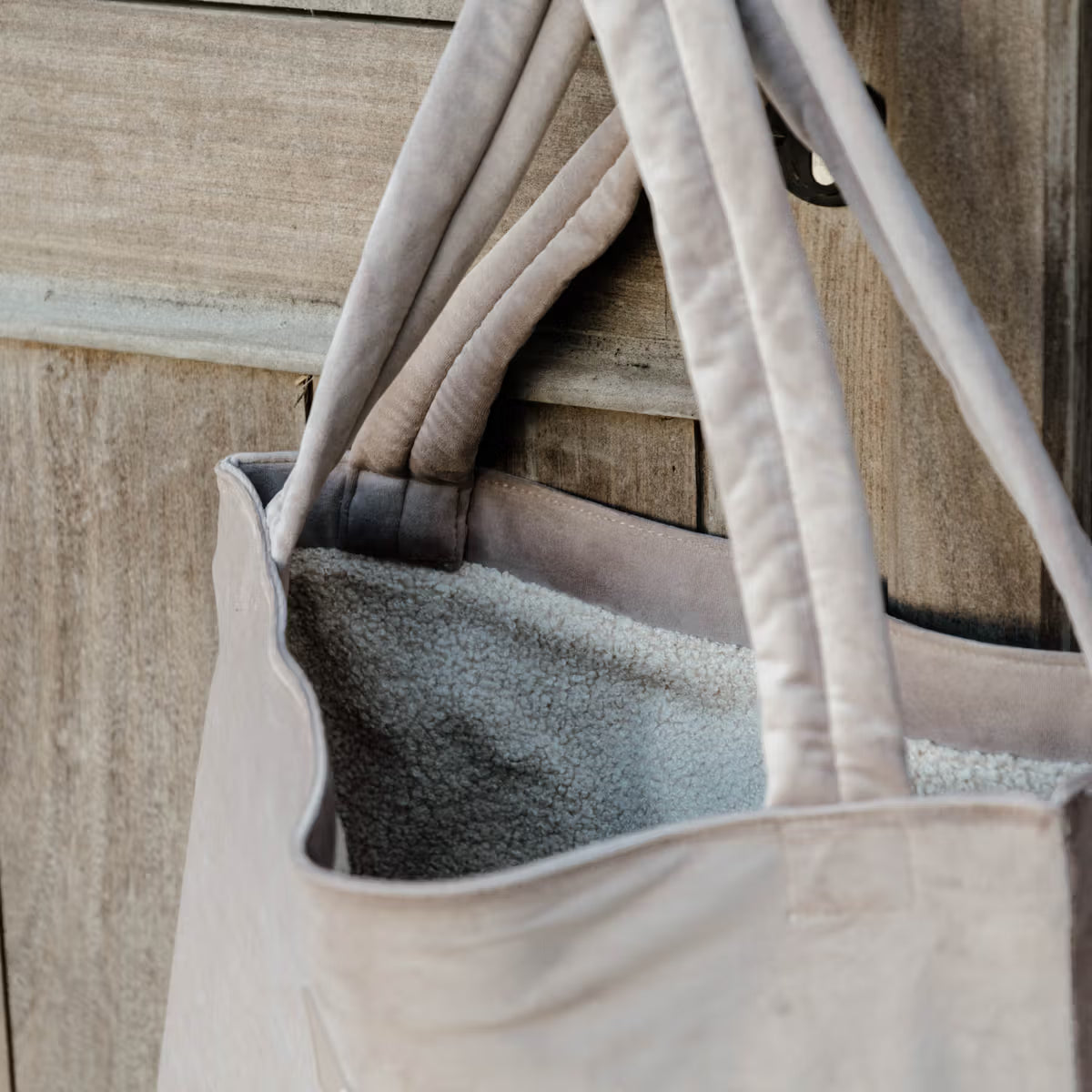 Beige tote bag with a blanket inside against a wooden background