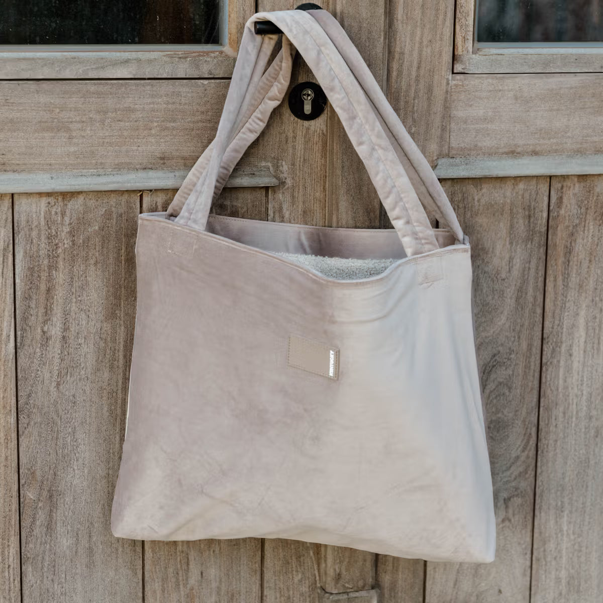 Beige tote bag hanging on a wooden door