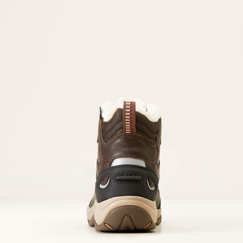Brown and black hiking boot with white sole on a beige background