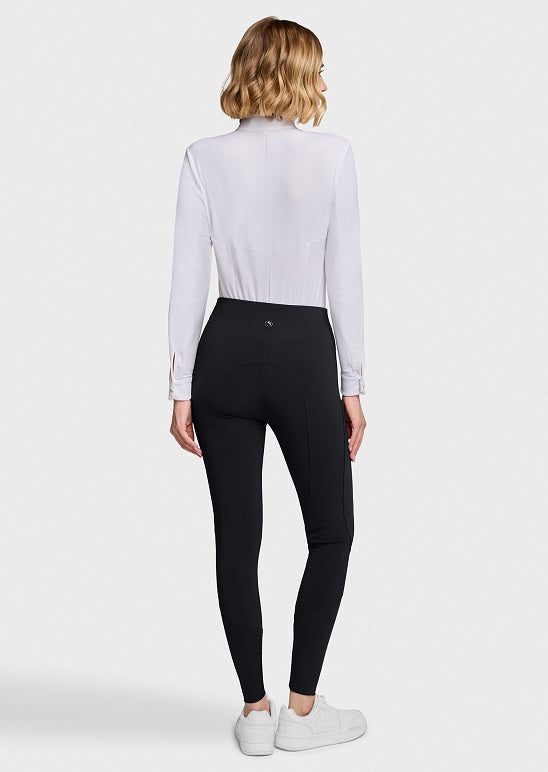 A woman shown from the back wearing a white long-sleeve mock-neck top, black high-waisted leggings, and white sneakers against a light gray studio background.