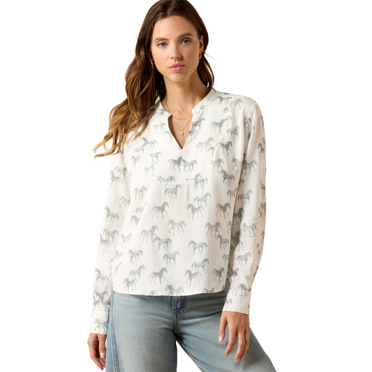 Woman wearing a white blouse with horse pattern and light blue jeans on a white background