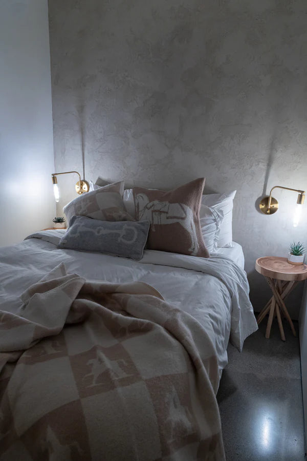 Beige throw on a bed with horse inspired cushions