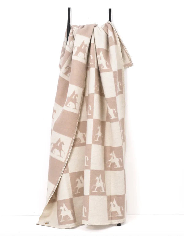 Beige throw hanging from a stand on a white background