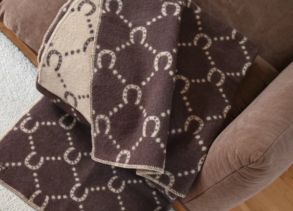 Brown and camel horse shoe blanket on a brown sofa 