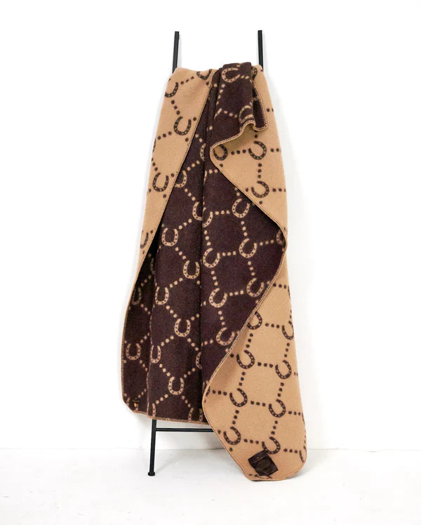 Horse shoe brown and camel blanket handing from a stand on a white backround