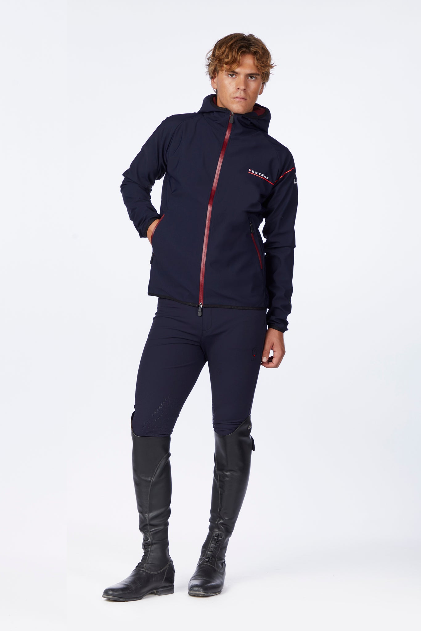 Person wearing a navy blue jacket and pants with black boots on a white background