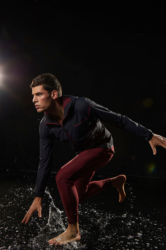 Man in athletic wear running through water on a dark background