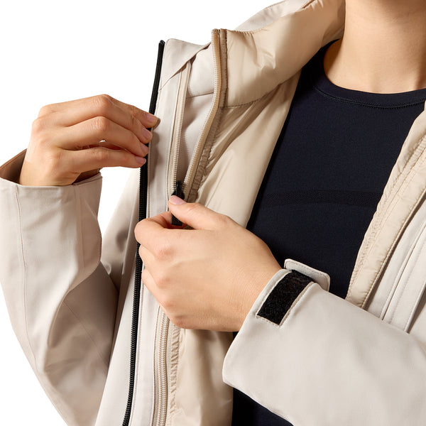 Close-up of a person wearing a light beige lightweight jacket over a dark navy shirt, showing the zipper and sleeve details.