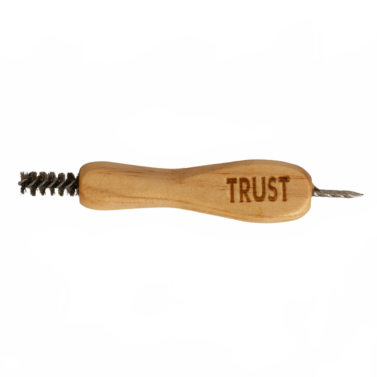 A wooden hand tool with a brushed metal wire brush on one end and a small metal pointed tip on the other, engraved with the word 'TRUST' on a plain white background.