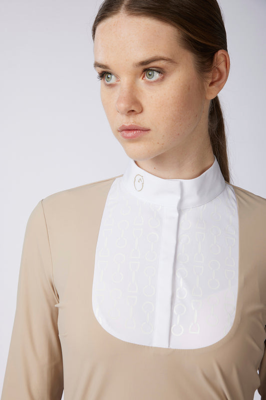 A close-up of a woman wearing a beige long-sleeve equestrian shirt with a white neck bib collar featuring a subtle embossed pattern.