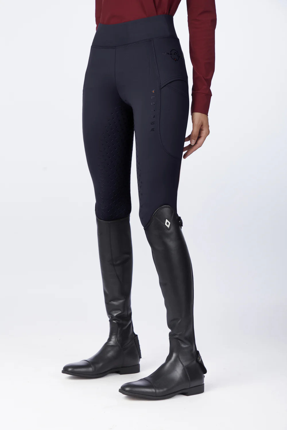Woman wearing navy tights and black riding boots on a white background