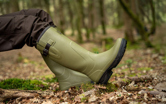 Person wearing green rubber boots in a forest setting