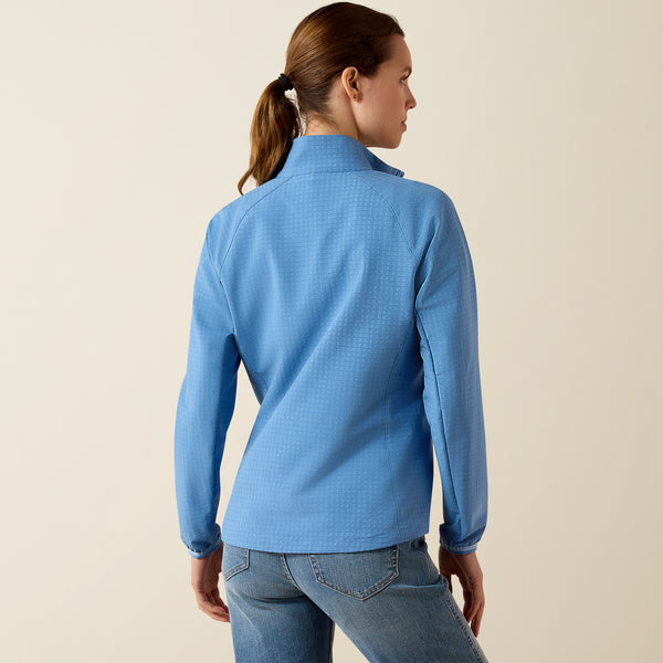 Woman wearing a blue long-sleeve jacket against a beige background