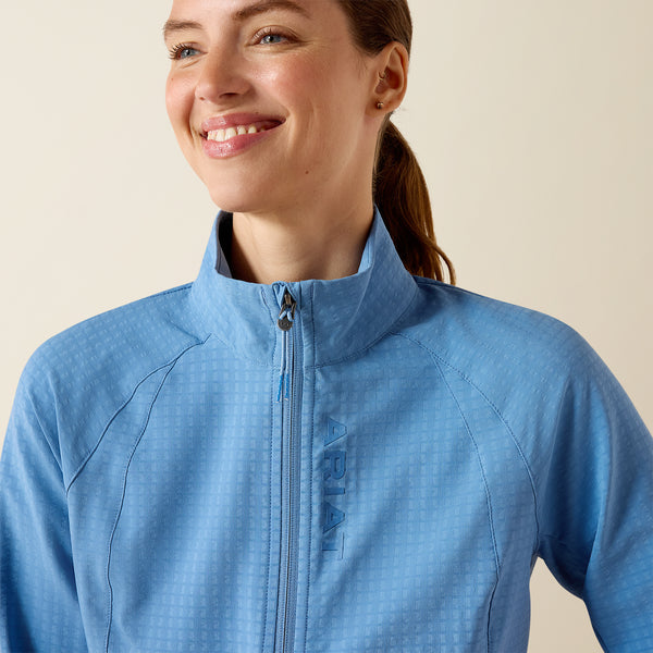 Woman wearing a blue jacket with a visible brand logo on a beige background