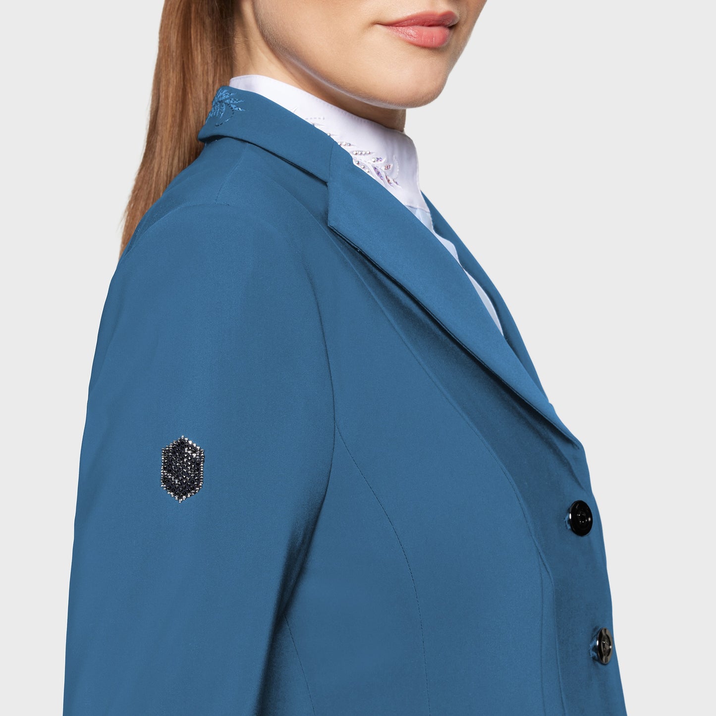 Blue competition jacket with decorative buttons on a plain background