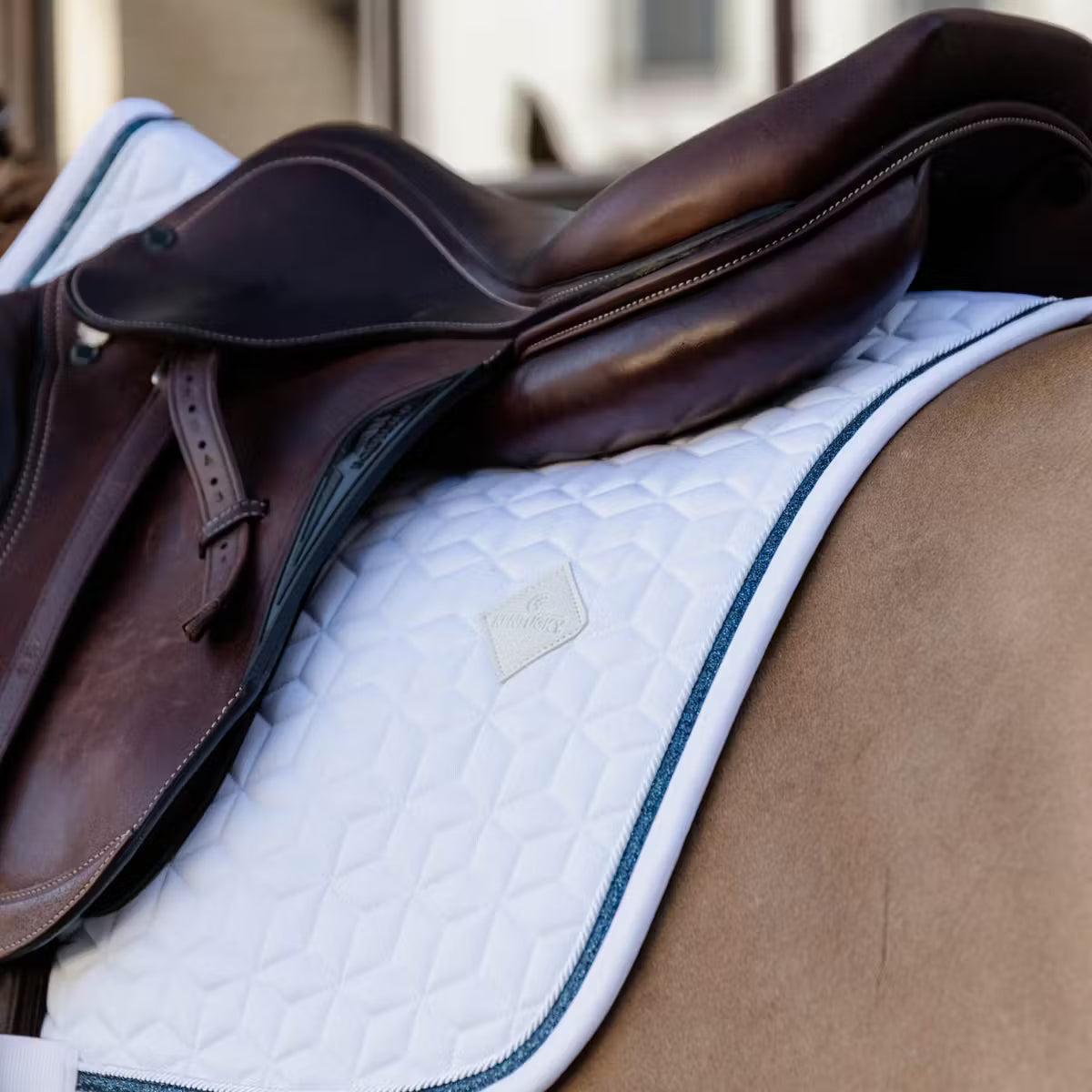 Brown saddle with a white saddle pad on a chestnut horse