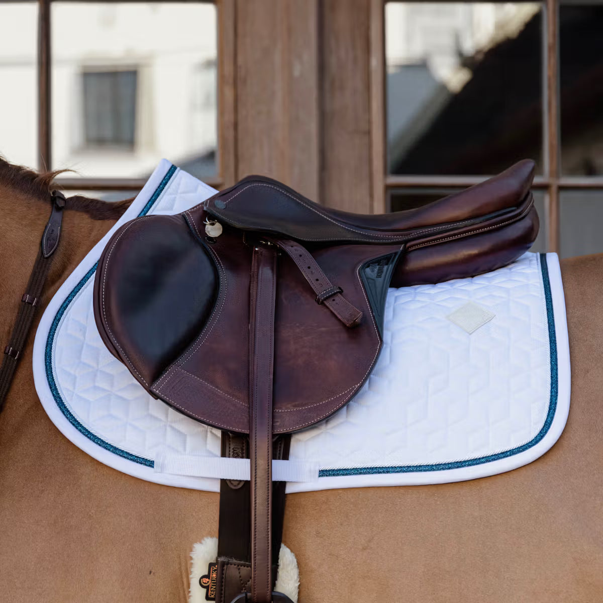 Brown saddle with a white saddle pad on a chestnut horse