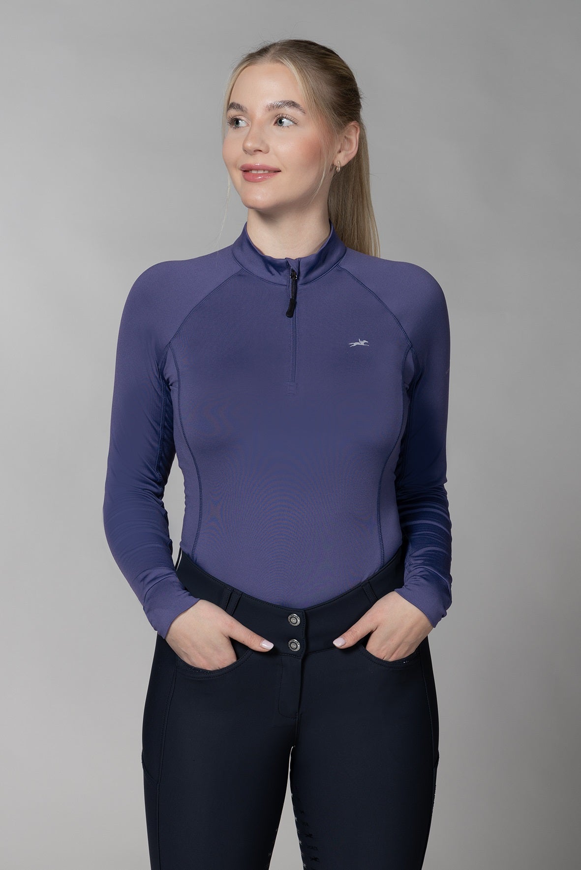 Woman wearing an ink blue long-sleeve top and black pants against a gray background