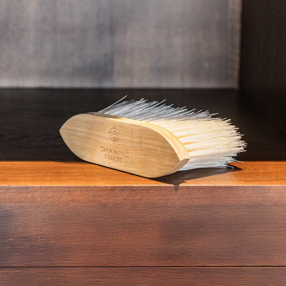 Wooden grooming brush with bristles on a wooden surface