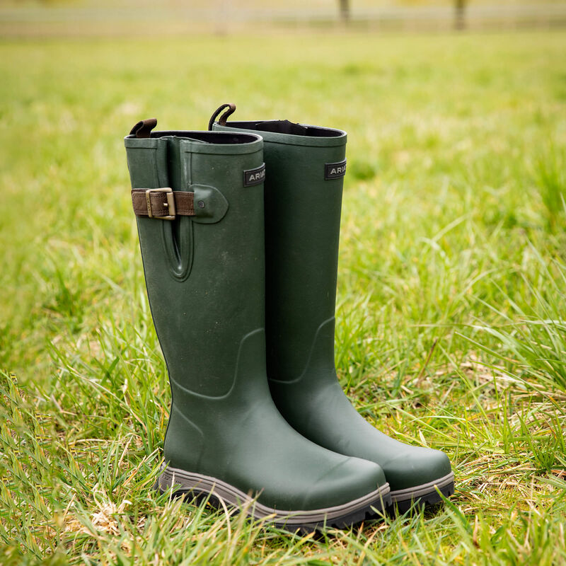 Green rubber boots with brown buckles on a grassy field