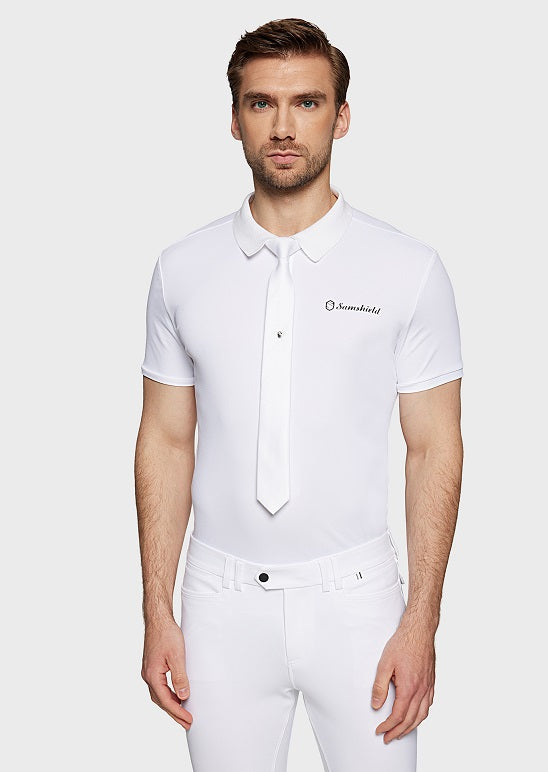 Man wearing a white polo shirt with a logo on a plain background