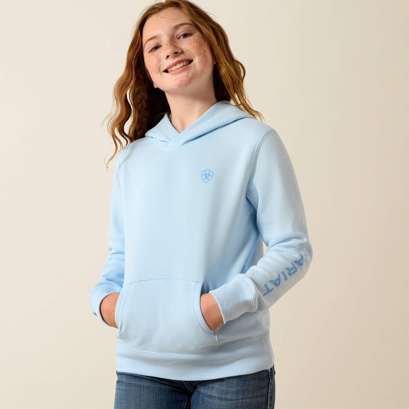 Person wearing a light blue hoodie with a logo on a beige background