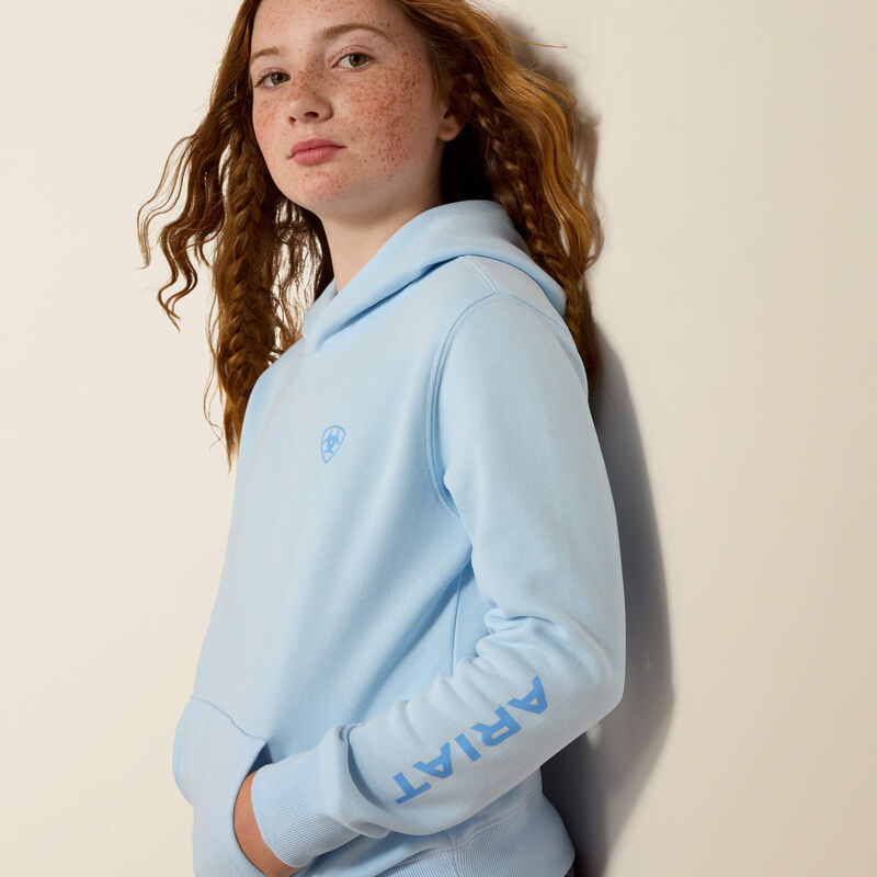 Person wearing a light blue hoodie with 'Ariat' branding against a beige background
