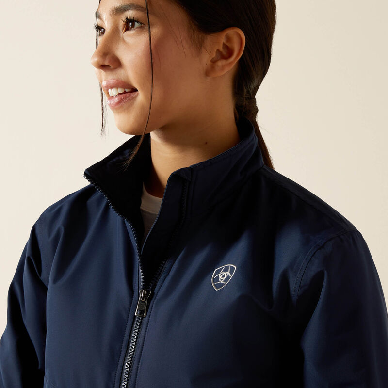 Woman wearing a navy blue jacket with a logo on a beige background